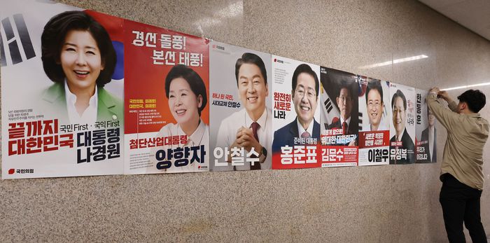 지난 20일 서울 여의도 국회 본청 국민의힘 사무실 앞에 당 관계자가 대선 경선 후보자 포스터를 붙이고 있다. [사진 출처 = 연합뉴스]