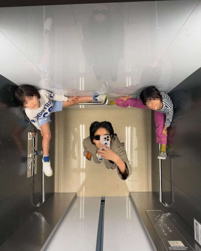 엘리베이터 거울 셀카 사진 속 아이들이 신발을 신은 채 손잡이에 올라탄 모습이 논란을 불러일으켰다.사진=김나영 SNS