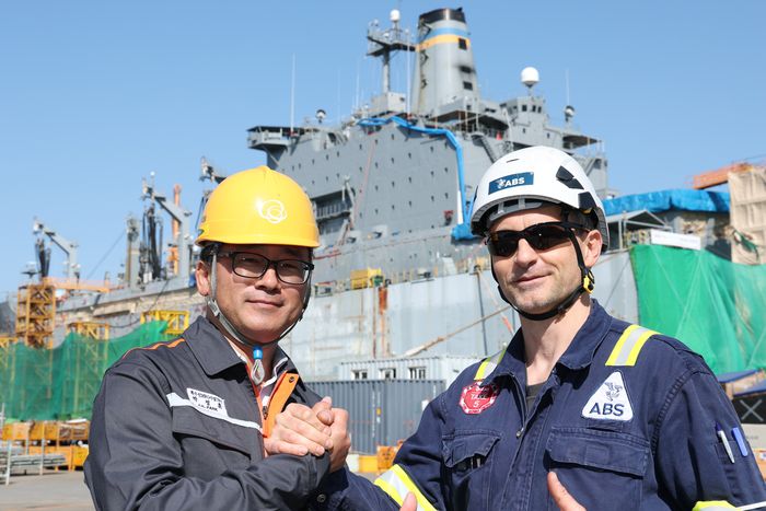 오른쪽 사진은 박정훈 한화오션 특수선 MRO TF팀 책임(왼쪽)과 볼로디미르 보로베츠 미국선급협회 (ABS) 수석검사관이 조선소에서 손을 맞잡은 모습. [사진 = 한화오션]