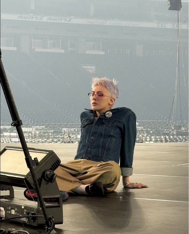 지드래곤은 단 한 개의 단추도 풀지 않은 데님 재킷을 입고 무대 바닥에 조용히 앉아 있다. 사진=지드래곤 SNS