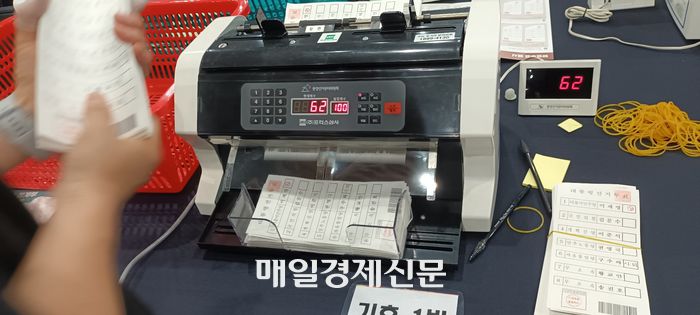 개표사무원들이 투표지심사계수기를 사용해  한 묶음으로 묶인 투표용지가 100장이 맞는지 재확인하고 있다. [사진 지혜진 기자]