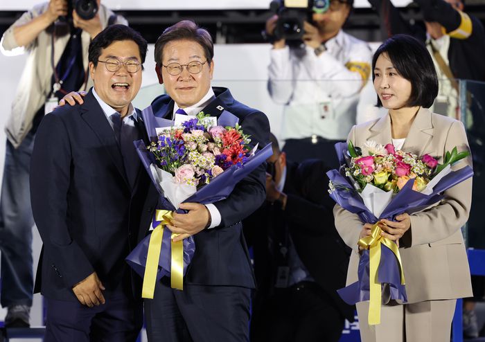 제21대 대통령에 당선된 이재명 대통령과 부인 김혜경 여사가 지난 4일 서울 여의도 국회 인근에서 당 주최로 열린 국민개표방송 행사에 참석해 박찬대 민주당 당대표 직무대행 겸 원내대표에게 꽃다발을 받고 있다. [사진 출처 = 연합뉴스]