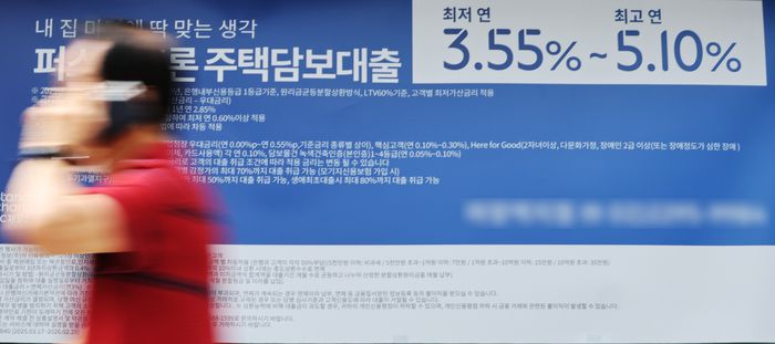 서울 시내 한 시중은행에 붙어 있는 주택담보대출 상품 현수막 앞으로 시민이 걸어가고 있다. [사진 = 뉴스1]