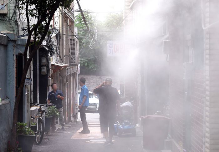 지난 8일 오후 서울 용산구 동자동 쪽방촌에서 주민들이 쿨링포그 아래에서 더위를 피하고 있다. [사진 출처 = 뉴스1]