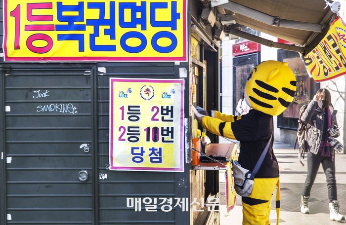 인형 탈을쓴 젊은 아르바이트생이 로또 복원을 구매하고 있다. [이충우 기자]
