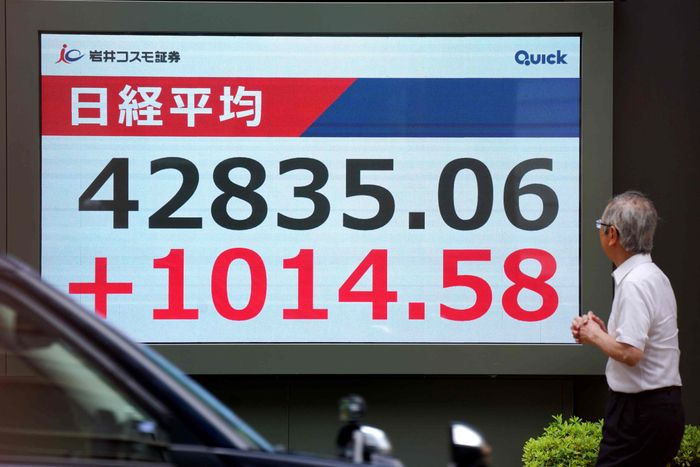 12일 닛케이지수가 1년여만에 사상 최고치를 경신한 가운데 도쿄 시민이 증권거래 현황판 앞을 지나가고 있다. [연합뉴스]