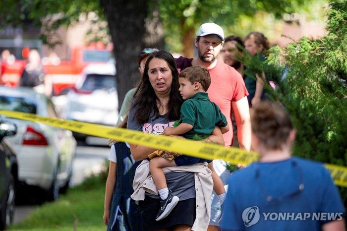 미국 미네소타주 미니애폴리스 초등학교에서 발생한 총기사건 후 한 아이가 아이를 끌어안고 사건 현장을 바라보고 있다. [사진출처=연합뉴스]