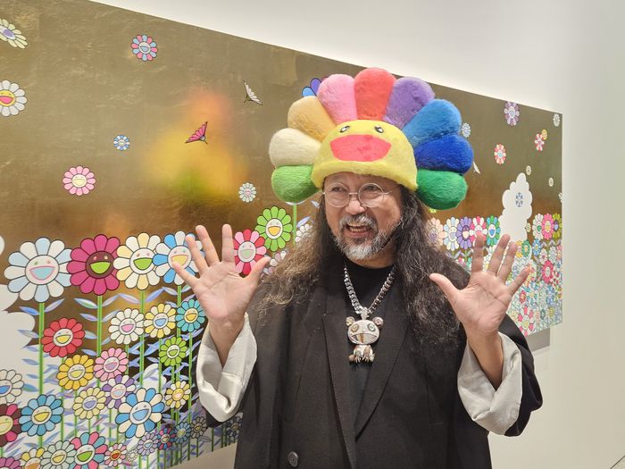 일본의 팝아트 거장 무라카미 다카시가 서울 용산구 아모레퍼시픽미술관(APMA) 캐비닛 전시장에 걸린 작품 앞에서 자신의 트레이드 마크인 ‘활짝 웃는 꽃’ 모자를 쓰고 포즈를 취하고 있다. 송경은 기자
