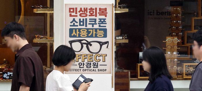 전 국민의 90%에게 오는 22일부터 2차 민생회복 소비쿠폰이 지급된다. 지급액은 1인당 10만원이다. 2차 소비쿠폰 지급이 발표된 12일 시민들이 소비쿠폰 사용이 가능함을 알리는 안내문 앞을 지나고 있다. [김호영 기자]