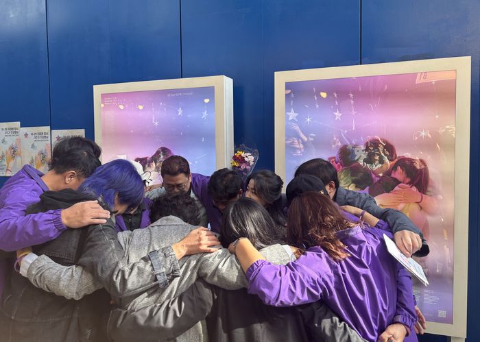 10.29 이태원 참사 3주기를 엿새 앞둔 23일 이태원 참사가 일어났던 이태원역 1번 출구 인근에 전시된 추모 사진 전시 앞에서 유가족들이 서로를 껴안고 있다. [연합뉴스]