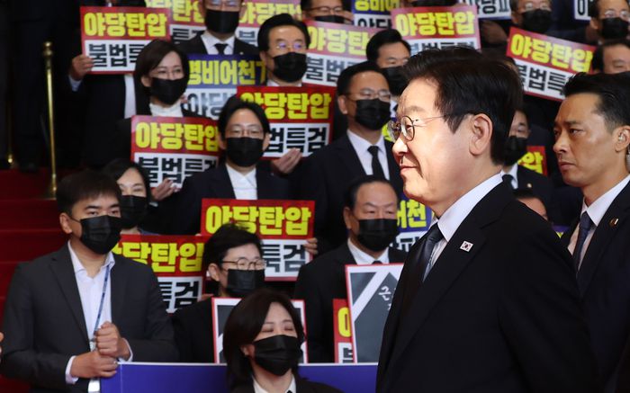 이재명 대통령이 4일 내년도 정부 예산안에 대한 시정연설을 하기 위해 서울 여의도 국회에 도착해 침묵시위를 하는 국민의힘 의원들 앞을 지나고 있다. 국민의힘 의원들은 추경호 전 원내대표에 대한 내란특검팀의 영장청구를 규탄하는 피켓을 들고서 침묵시위를 했다. [국회사진기자단]