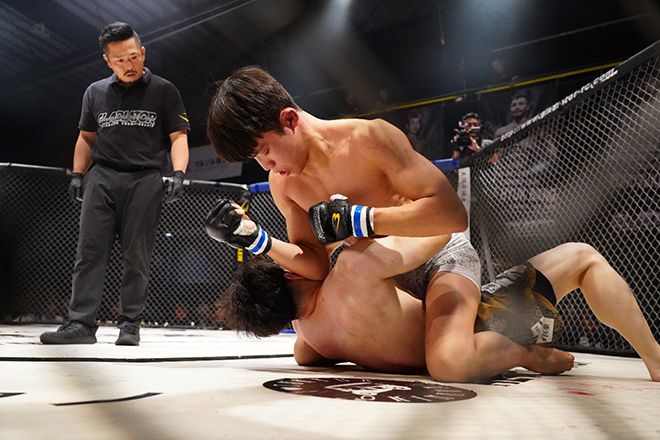 KMMA 페더급 타이틀 도전 예정자 김지경이 2025년 9월 일본 오사카 글래디에이터 032에서 ‘약사 파이터’ 아마노 다케노리를 공격하고 있다. 아마노는 일본 가라테 전설이자 추성훈의 종합격투기 상대였던 도노오카 마사노리의 제자다. 사진=대구반월당역 뽀빠이연합의원 제공