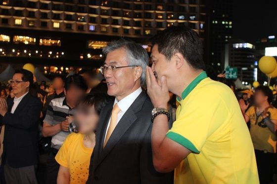 이혁진 옵티머스 전 대표가 2012년 고(故) 노무현 전 대통령 3주기 추모공연에서 문재인 당시 민주통합당 의원에게 귓속말을 건네고 있다.