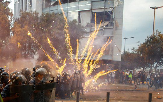 10일 레바논 반정부 시위대가 격렬한 시위를 벌이는 가운데 경찰과 충돌하고 있다. 시위대가 던진 폭죽이 화염을 일으키고 있다. [로이터=연합뉴스]