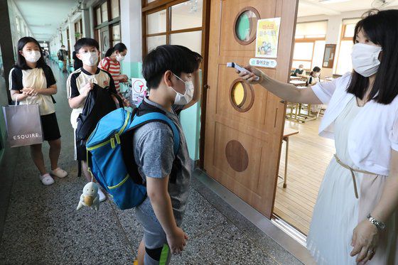 여름방학을 마치고 개학한 18일 오전 대구의 한 초등학교 교실 앞에서 담임 교사가 학생들의 체온을 측정하고 있다. 뉴스1