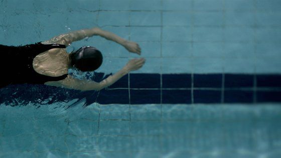 성폭행 사건 후 수영하는 효정의 뒷모습. 임선애 감독은 "효정에게 수영은 무릎 관절 때문에 그나마 할 수 있는 운동이고 마지막 돌파구"라면서 "사건 경험 직후엔 효정이 팔다리를 움직일 수 없을 만큼 무력감이 들지 않을까, 생각해 물에 몸을 맡긴 채 죽은 듯이 떠가는 이미지를 만들고 싶었다"고 했다. 수영은 그가 "실제 주변 장년 여성들이 무리 없는 운동으로 즐기는 걸 보고 택한 설정"으로, "가라앉지 않으려면 팔다리를 열심히 움직여야만 하고 몸을 움직여야 어떤 목표에 도달하게 된다"는 수영의 속성은 성폭행 사건 후 효정의 고군분투와 연결되기도 한다. [사진 엣나인필름]