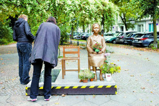 9일(현지시간) 독일 베를린에 있는 ‘평화의 소녀상’ 앞에 멈춰 서 비문을 읽고 있는 시민들. 일본군 위안부 피해자를 기리기 위한 조형물이지만 시 당국이 철거를 명령했다. [AP=연합뉴스]