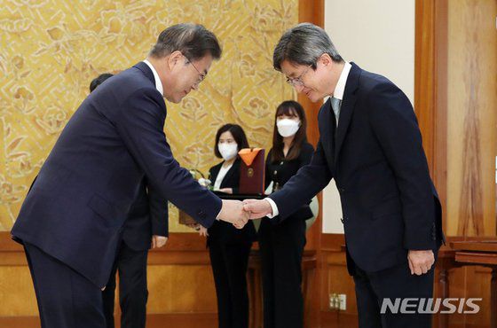 문재인 대통령이 지난해 5월22일 청와대에서 열린 퇴임 대법관 훈장 수여식에 참석해 김명수 대법원장과 악수하고 있다. 뉴시스