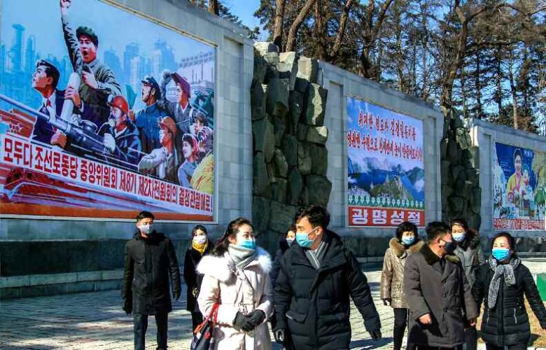 노동신문이 17일 공개한 사진속에 길을 걷는 북한 주민들 뒤로 노동당 중앙위원회 제8기 제2차 전원회의 결정을 관철하자는 선전화가 걸려 있다. 노동신문=뉴스1