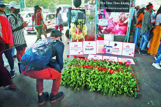 21일 미얀마 최대 도시 양곤에서 한 시민이 쿠데타 반대 시위 도중 머리에 총탄을 맞고 뇌사 상태에 빠졌다 열흘 만에 숨진 20세 여성의 추모 제단에 헌화하고 있다. 미얀마에선 군경이 시위대에 발포해 4명 이상이 숨졌다. [AP=연합뉴스]