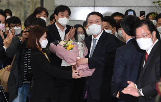 지난 4일 사의를 표명한 윤석열 검찰총장이 직원들과 인사를 나눈 뒤 꽃다발을 들고 대검찰청 청사를 나서고 있다. 김경록 기자