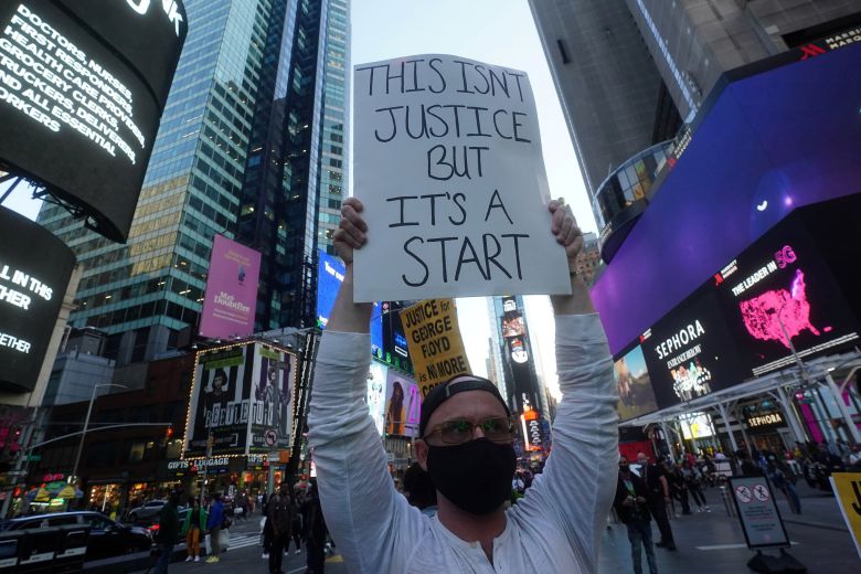 한 뉴욕시민이 20일 타임즈 스퀘어에서 "아직 정의가 아니다. 시작일 뿐"이라고 쓴 플래카드를 들고 있다. 로이터=연합뉴스