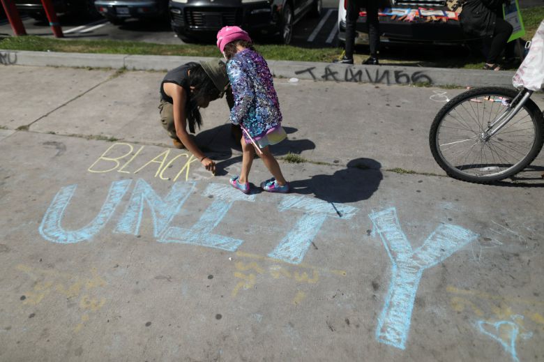 미국 캘리포니아 시민이 20일 데릭 쇼빈에 대한 유죄 평결 뒤 거리에 분필로 "흑인, 단합"이라는 글씨를 쓰고 있다. 로이터=연합뉴스