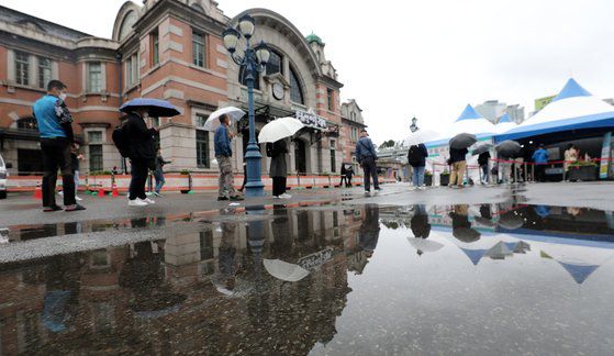 21일 서울 중구 서울역광장에 마련된 신종 코로나바이러스 감염증(코로나19) 임시 선별검사소에서 우산을 쓴 시민들이 검사를 기다리고 있다. 뉴스1