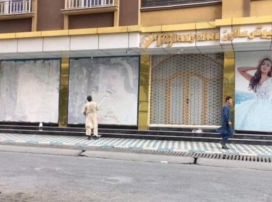 15일(현지시각) 톨로뉴스TV 대표 로트풀라 나자피자다가 트위터에 올린 사진. 히잡을 쓰지 않은 여성이 그려져 있던 벽화를 한 남성이 흰 페인트로 칠하고 있다. [로트풀라 나자피자다 트위터 캡처]