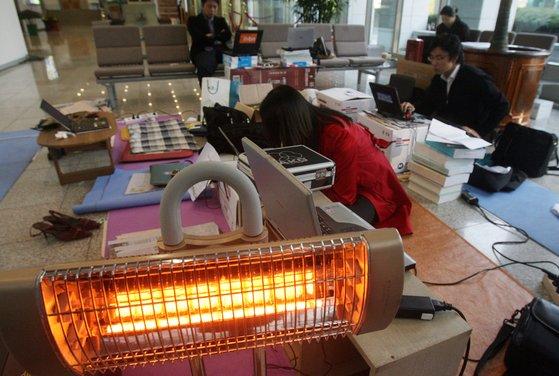 노무현 정부 시절 국정홍보처의 기존 출입증 무효 조치에 따라 2007년 11월 외교통상부 출입기자들이 청사 복도 바닥에 앉아 기사를 작성하고 있는 모습. 중앙포토