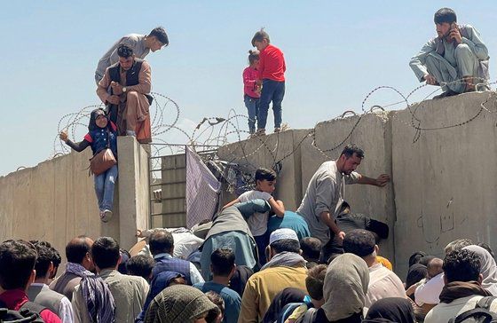16일(현지시간) 아프가니스탄 수도 카불의 하미드 카르자이 국제공항에서 국외 탈출을 위해 주민들이 담을 넘어 공항으로 들어가고 있다. [로이터=연합뉴스]