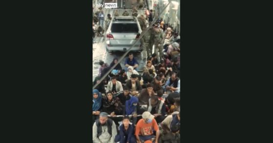 영국으로 향하는 군 수송기 내부에 차량 한 대가 실려 있고 그 주변으로 사람들이 앉아 있다. [스카이뉴스 캡처]