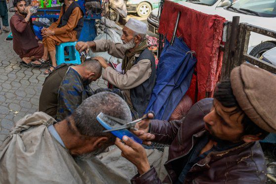 지난 22일 아프가니스탄 수도 카불에서 거리 이발사들이 손님의 머리를 다듬고 있다. AFP=연합뉴스
