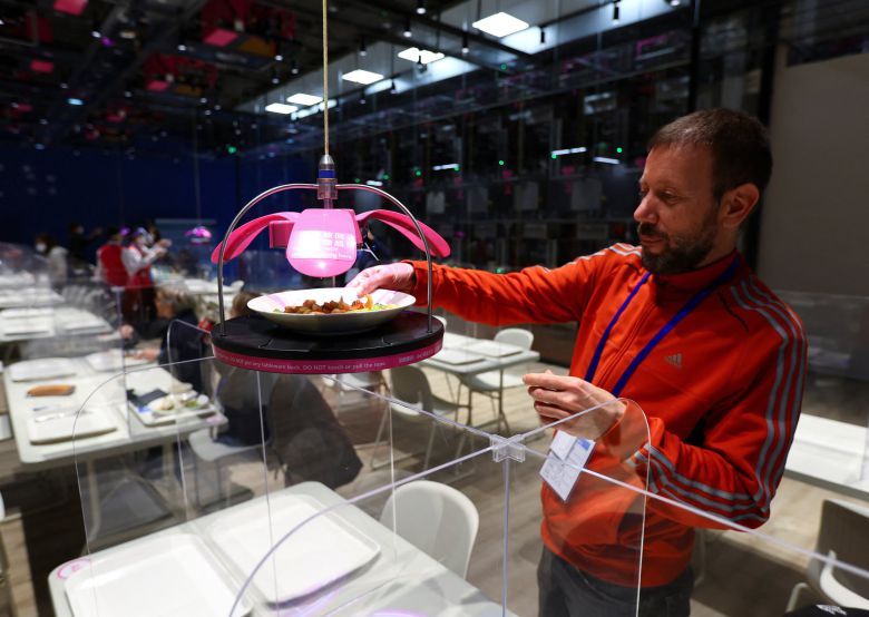 베이징올림픽 메인 프레스 센터 식당을 방문한 취재진이 로봇을 활용한 자동 조리 과정을 거쳐 천장으로 테이블까지 자동으로 배달되는 음식을 받아들고 있다. [로이터=연합뉴스]