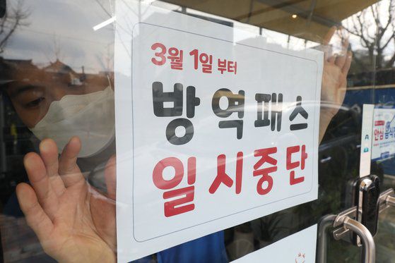 지난달 28일 오후 대구 중구의 한 음식점 유리문에 식당 직원이 3월 1일부터 시행되는 방역패스 일시중단 관련 안내문을 붙이고 있다. 뉴스1