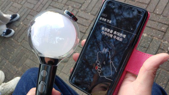 BTS 공식 굿즈는 경기장 앞에서 팔지 않고, 잠실 롯데몰에 마련된 스토어에서만 판매했다. 공식 조명은 핸드폰 앱과 연동해, 공연장 좌석 위치에 따라 노래에 맞춰 변할 수 있도록 했다. 사진은 한 팬이 공식 조명 응원봉을 핸드폰 앱과 연결하는 장면. 김정연 기자