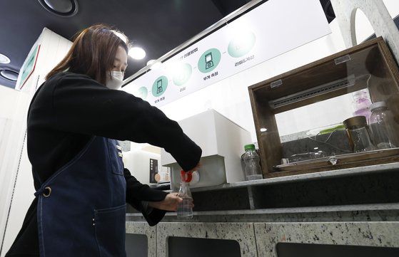 지난해 12월 21일 오후 일회용 포장재를 사용하지 않는 제로웨이스트 상점인 ’제로마켓’ 서울 홈플러스 월드컵점에서 한 관계자가 리필스테이션을 이용해 세제를 용기에 담고 있다.   제로마켓'은 세제, 샴푸, 화장품 등 리필이 가능한 제품을 구매할 때 필요한 만큼만 무게를 재서 살 수 있는 친환경 매장이다. [연합뉴스]