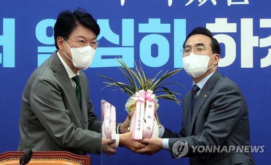 박홍근 민주당 원내대표(오른쪽)가 25일 국회 원내대표 회의실에서 장제원 대통령 당선인 비서실장으로부터 윤석열 당선인의 축하 난을 받고 있다. 연합뉴스