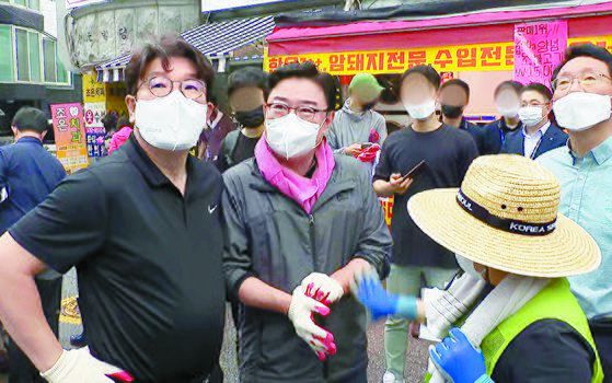 국민의힘 김성원 의원(가운데)이 지난 11일 수해 복구 자원봉사를 위해 당 지도부와 찾은 서울 동작구 사당동에서 권성동 원내대표(왼쪽) 등과 대화하고 있다.   김 의원은 "솔직히 비 좀 왔으면 좋겠다. 사진 잘 나오게"라고 발언해 각계에서 비판을 받았다. 사진 유튜브 캡처