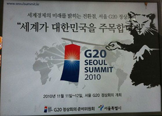 2010년 G20 포스터에 도안을 대고 검정색 스프레이를 뿌리는 방식으로 그린 ‘쥐 그림’. 트위터 캡처