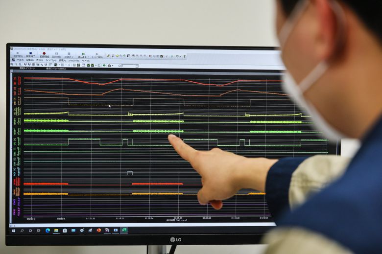 관계자가 시험 가동 중인 중입자가속기를 모니터링 하고 있다.