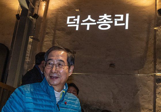 한덕수 국무총리가 18일 오전 서울 동대문구 경동시장 내 스타벅스 '경동1960'점을 찾아 주문한 커피가 준비되자 구매대로 이동하고 있다. 뒷편 벽에는 닉네임 '덕수총리'가 표시돼 있다. 연합뉴스