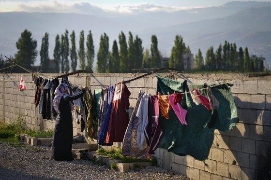 시리아 난민 여성이 레바논의 난민캠프에서 가족의 빨래를 텐트 밖에 널고 있다.AP=연합뉴스