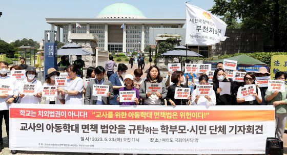 교사의 아동학대 면책 법안을 규탄하는 학부모·시민단체가 23일 서울 여의도 국회 앞에서 '초·중등교육법 일부개정 법률안' 발의 규탄 기자회견을 하고 있다.  단체는 국민의힘이 발의한 법안이 자칫 아동학대를 조장할 수 있다며 우려를 표했다. 뉴스1