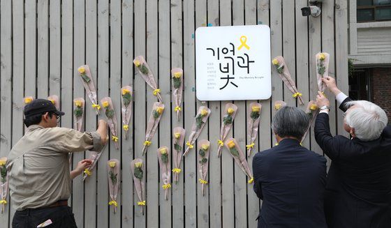 4.16세월호참사가족협의회와 4.16연대 회원들이 지난 5월 서울 중구 서울시의회 앞에서 가진 4.16세월호참사 10주기 위원회 발족 기자회견에서 세월호 추모공간에 노란 꽃을 붙이고 있다. 뉴스1