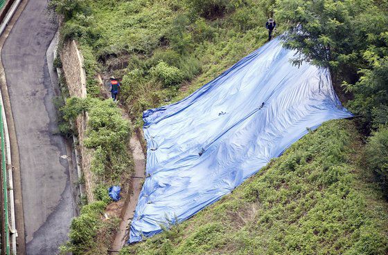 24일 광주 북구 연제동 한 공동주택 인근 경사지에서 북구청 공원녹지과 직원들이 토사 유실 예방을 위한 방수포를 설치하고 있다. 북구 제공.
