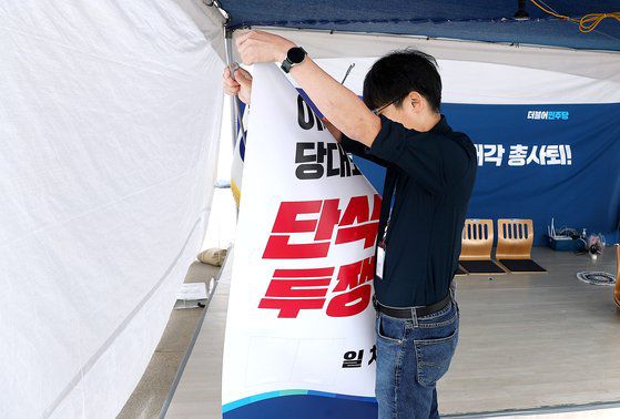 더불어민주당 한 관계자가 25일 오전 국회 본청 앞에서 이재명 대표가 단식 투쟁을 했던 천막과 현수막 등을 철거하고 있다. [뉴시스]