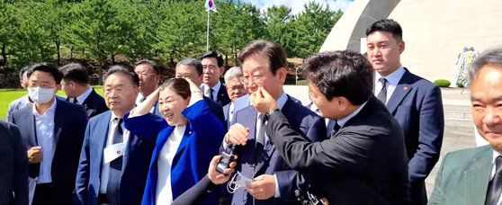 지난 2022년 8월 제주도 제주 4·3 평화공원에서 박찬대 더불어민주당 의원이 이재명 당시민주당 대표 후보의 광대뼈에 묻은 이물질을 떼는 모습. 사진 유튜브 채널 ‘정치타파TV’ 캡처