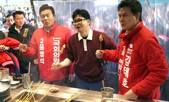 국민의힘 한동훈 비상대책위원장이 26일 오후 경남 양산시 양산남부시장을 찾아 같은 당 김태호, 윤영석 후보와 함께 어묵을 먹고 있다. 연합뉴스