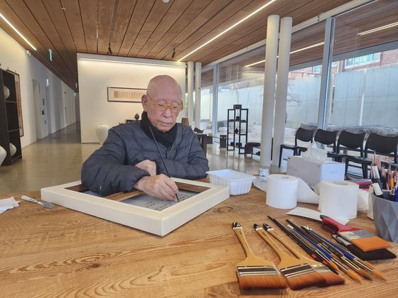 자신의 작품 뒤에 서명하는 박서보. [사진 박서보재단]